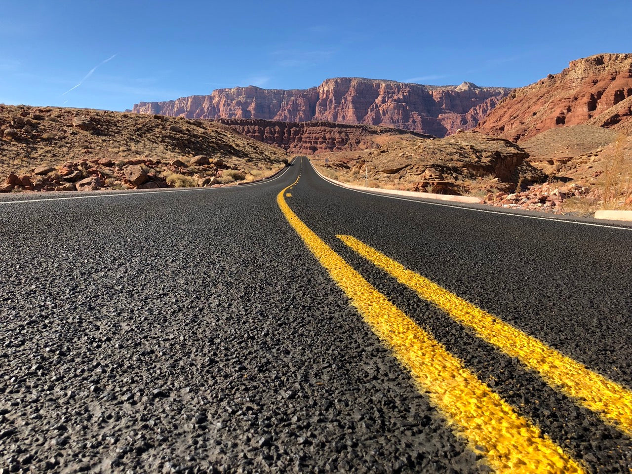 view along an asphalt road with yellow lane markers in the middle